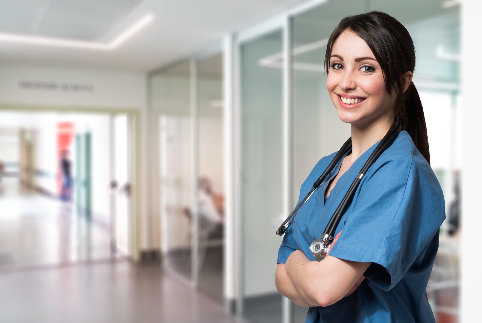 Smiling nurse in hospital corridor with medical team — acute care facility partnership