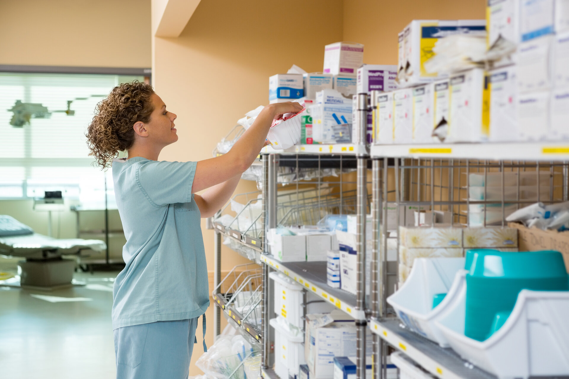 Healthcare professional managing medical supply inventory on shelving unit