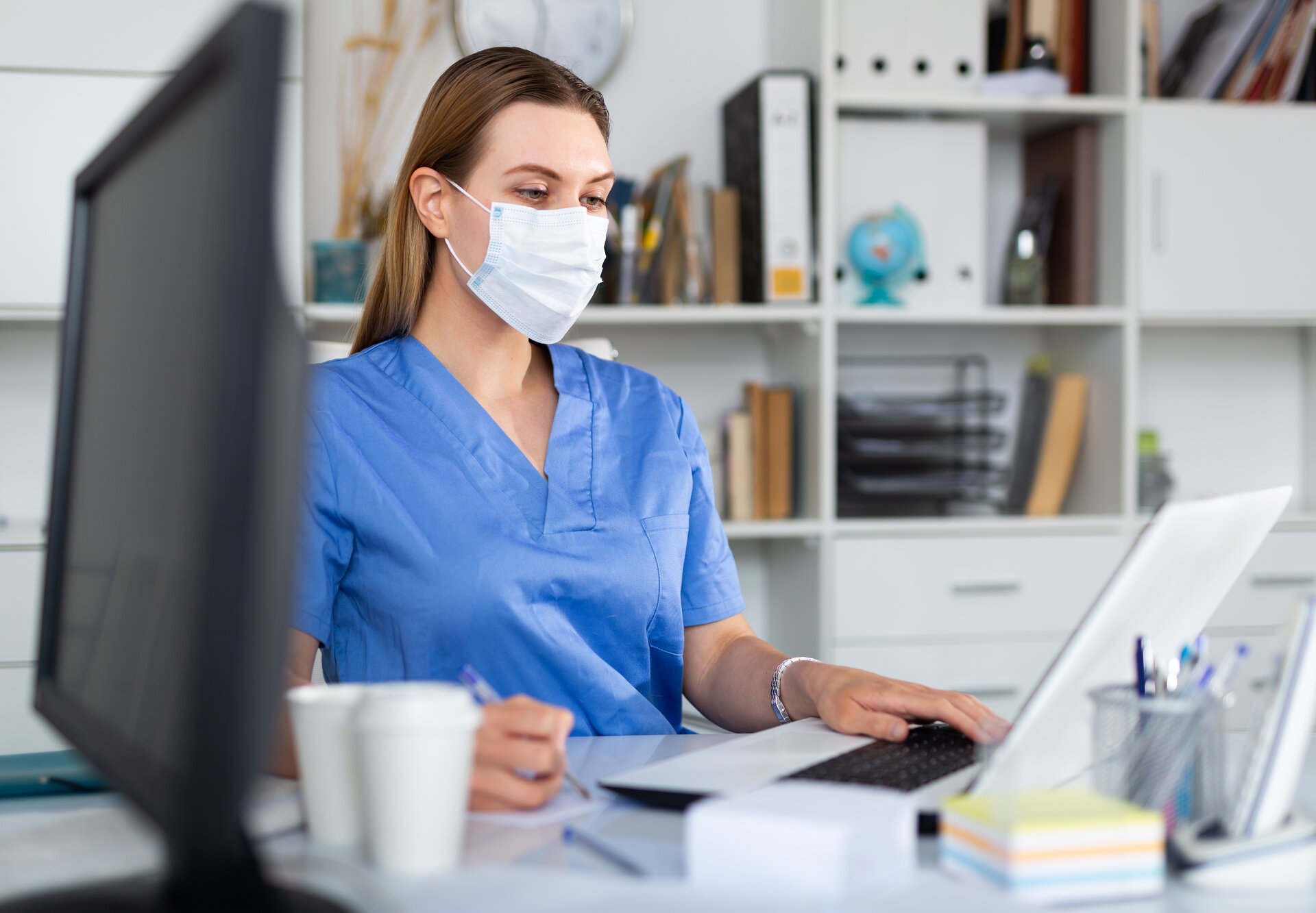 Healthcare professional reviewing patient records and documentation at workstation