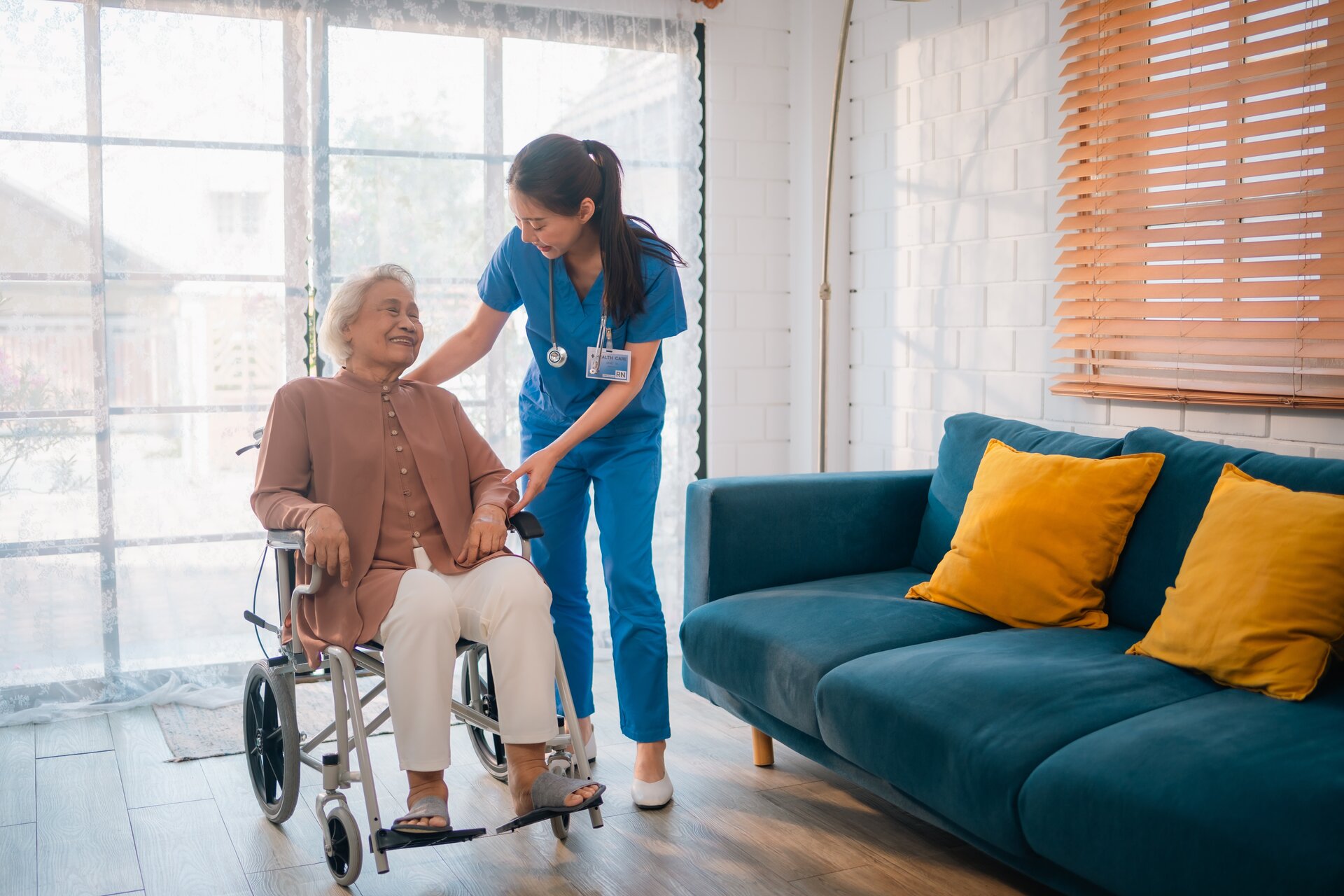 Nurse caring for smiling elderly patient in wheelchair at home