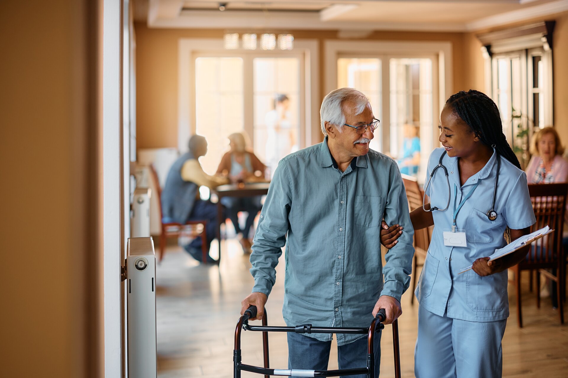 Nurse assisting elderly patient with walker in long-term care facility